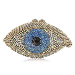 Golden eye shaped evening clutch bag with blue and white crystals on white background