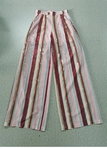 Dettaglio di pantaloni larghi a paillettes a righe colorate con vita alta lucida
