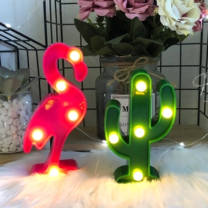Pink flamingo and green cactus LED night lights with warm yellow bulbs on white fur