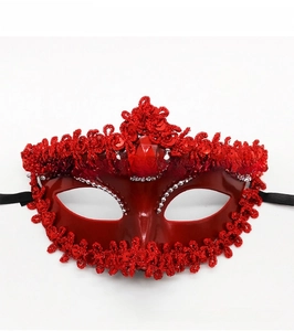 Macro detail of red masquerade mask with lace trim, silver bead chains and large central gem