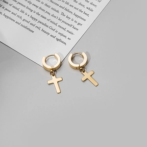 Detail of a polished gold cross pendant earring on a minimalist background card