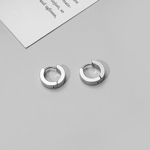 Detailed top view of a pair of silver stainless steel hoop earrings on minimalist background