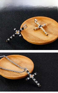 Detail of mechanical cross pendant featuring textured cylinders and rope chain