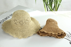 Dettaglio di cappelli di paglia fatti a mano con tesa larga ondulata in beige e caramello