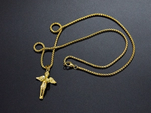 Detailed close-up of golden angel pendant with box chain over a dark textured surface