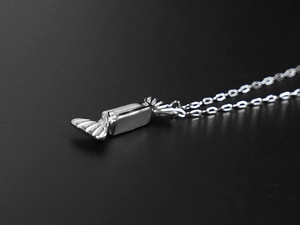 Macro view of a silver-toned candy-shaped pendant on a titanium steel necklace