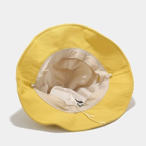 Detail of yellow cotton bucket hat showing interior lining and adjustable drawstring