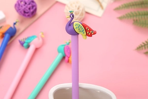 Close-up of a purple cartoon peacock gel pen in a white holder with soft desk decor