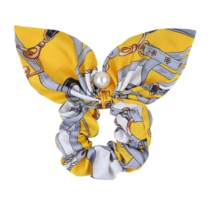 Detail of yellow floral bow hair tie featuring grey chain pattern and white pearl bead