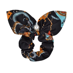 Detail of black silk scrunchie with colorful prints, bow tie and pearl pendant charm