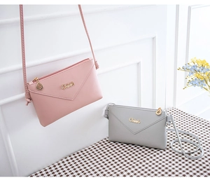 Close-up of minimalist faux leather phone bag with V-shaped flap and leaf metal pendant