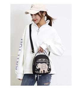 Detail of black nylon backpack with elegant beige elephant embroidery and gold hardware