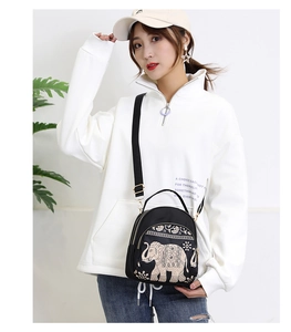 Model wearing a black water-resistant nylon crossbody bag with gold elephant pattern print