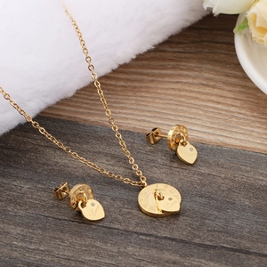 Golden Roman numeral and heart love necklace and earrings set on a wooden surface