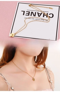 Detailed view of a gold Roman numeral coin necklace showing pendant and model wearing it