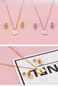 Detail view of gold and silver heart necklaces with Roman numeral disc earrings set