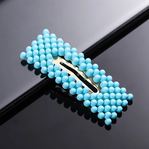 Detailed view of rectangle gold hair clip with dense blue spherical bead embellishments