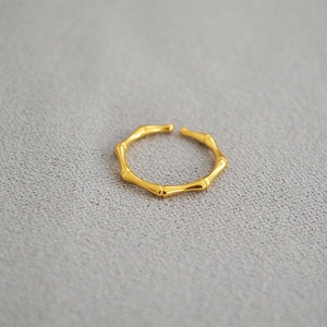 Modern gold plated brass bamboo joint open ring for women on grey fabric background