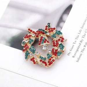 Close-up of a Christmas wreath brooch with colorful rhinestones and a gold bell