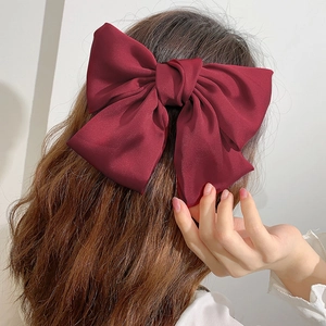 Oversized wine red satin bow hair clip for women shown on back of head for styling