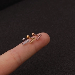 Three-color stainless steel bar stud earrings with clear zircon stones on a finger