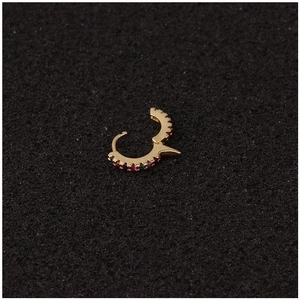 U-shaped gold cuff earring with colorful zircons and metal spikes on dark background