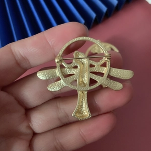 Detailed back view of gold dragonfly brooch showing secure horizontal safety pin clasp