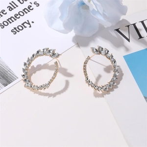 Detail of luxury gold hoop earrings featuring marquise-cut crystals on a stylish background