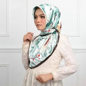 Detail of satin scarf with green leaf and berry print worn as a headscarf