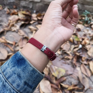 Close-up of red leather watch strap with silver buckle worn on a wrist outdoors