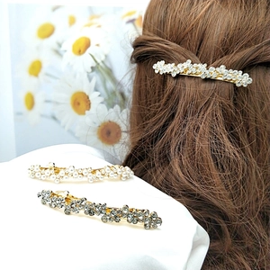 Détail de barrettes dorées avec cristaux et perles sur mannequin et tissu blanc