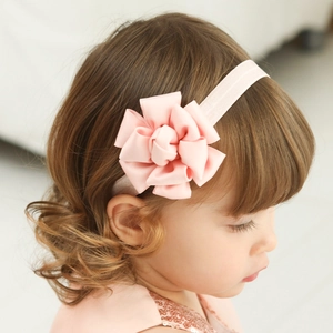 Close-up of baby girl wearing a soft pink satin fabric flower headband on a stretchy band