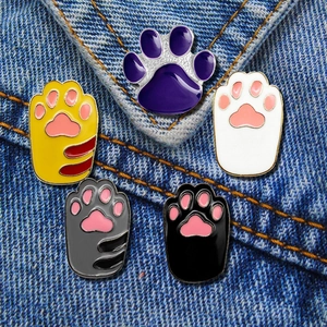 Detail of colorful cat paw enamel pins on denim fabric showing various cute color patterns