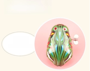 Classic mechanical clockwork frog toy with green patterns and silver wind-up key on pink background