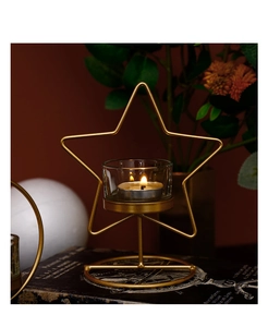 Dettaglio macro del portacandele dorato a forma di stella con bicchiere e luce calda accesa