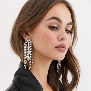 Close-up of silver long tassel earrings with pearls and rhinestones on a female model