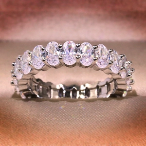 Macro shot of silver ring with oval-cut cubic zirconia stones on soft fabric