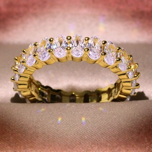 Macro shot of gold band ring with pavé-set oval zircons on luxurious silk fabric