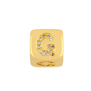 Macro shot of gold-plated cubic charm bead with sparkling cubic zirconia letter G