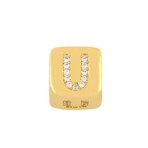 Close-up of a gold cube charm featuring a sparkling letter U set with small zircons
