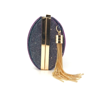 Dettaglio di una borsa da sera in raso viola con frange dorate e montatura metallica chic