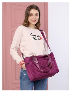 Detail of purple nylon tote bag featuring adjustable embossed strap and side zipper pocket