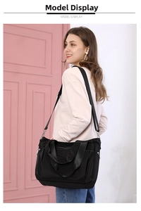 Lightweight black nylon tote bag worn by model featuring adjustable strap and side pocket