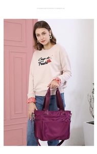 Close-up of purple nylon tote bag with durable webbing handles and detachable shoulder strap