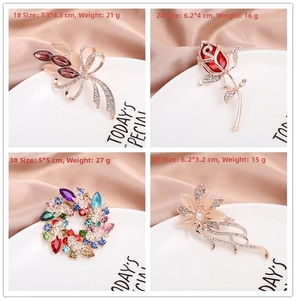 Detail showcasing assorted crystal floral and butterfly brooches with size and weight specs