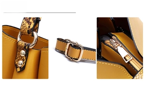 Detail of yellow bag with snake pattern texture and gold-tone metal hardware and zipper