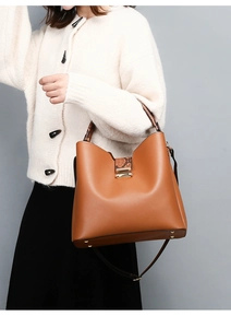 Brown tote bag with snake pattern details shown on model with beige knit sweater