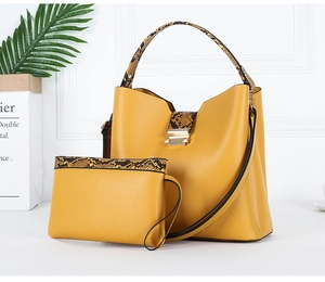 Detail view of yellow leather bucket handbag and matching pouch with snakeskin trim