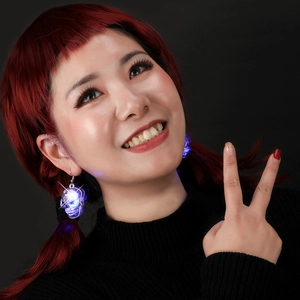 Detail of transparent skull earrings with glowing blue LED light on professional model