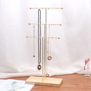 Three-tier gold metal necklace display stand with multiple hooks and natural wood base
